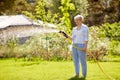 Senior woman watering lawn by hose at garden Royalty Free Stock Photo