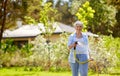 Senior woman watering lawn by hose at garden Royalty Free Stock Photo