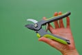 Gardening Tools. Garden shears in female hands on a green background.Gardening and horticulture. Garden Plants Pruning