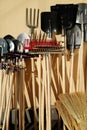 Gardening tools: shovels, rakes, brooms displayed against a wall on a sunny day. Storage or sale Royalty Free Stock Photo