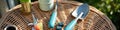 Gardening tools on wicker table in outdoor setting with greenery in background Royalty Free Stock Photo