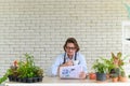 Gardening wearing glasses and denim apron sitting and drinking coffee while reading newspaper in his home gardening. retirement Royalty Free Stock Photo