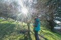 Backlit worker pruning fruit tree branches with a lopper