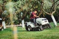 Gardening with worker using a ride on tractor, mower for cutting grass Royalty Free Stock Photo