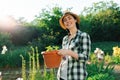 Gardening. A young happy Caucasian woman in a straw hat holding a pot of seedlings. Earth Day concept Royalty Free Stock Photo