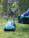 A gardener attaching empty grass basket to electric lawn mower machine