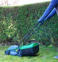 A gardener moving a electric lawn mower machine to cut the grass