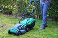 A gardener moving an electric lawn mower machine to cut the grass.