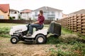 Gardner trimming and unloading cut grass from the garden using a ride on lawn mower Royalty Free Stock Photo