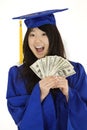 Asian teenage in blue graduation gown holding US money