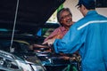 Gargae customer and car mechanic together investigate maintenance and repair programe at garage and car maintenance station Royalty Free Stock Photo