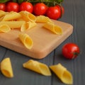 Garganelli pasta on the kitchen board behind the tomatoes