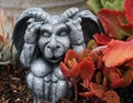 Gargoyle statue crouches nea small, red  plant Royalty Free Stock Photo