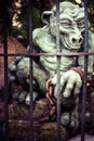 Monster statue behind bars in garden.