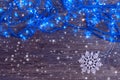 Garland with blue lights and a white snowflake on a wooden background. Christmas and New Year background.