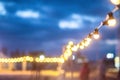 Garland of glowing electric bulbs on the background of the evening sky. Shallow depth of field