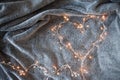 Garland heart with glowing lights in the background of a fluffy grey blanket