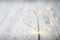 Garland lights in the shape of a heart on a white wooden table. The concept of love and Valentine`s day Royalty Free Stock Photo