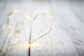 Garland lights in the shape of a heart on a white wooden table. The concept of love and Valentine`s day Royalty Free Stock Photo