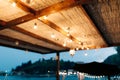 Garland on a wire of Led-light bulbs, under a thatched roof.