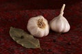 Garlic, bay leaf, black pepper on a red textile. Food background. Garlics. sliced garlic, garlic clove, garlic bulb.