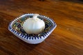 A garlic bulb in a decorative bowl on a wooden table. Royalty Free Stock Photo