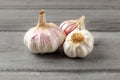 Garlic bulbs, purple cloves under cracked skin on gray wood tabl