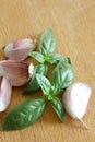 Garlic cloves and basil leaves on a wooden cut board