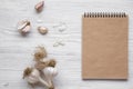 Garlic cloves, garlic bulbs and blank notepad on white wooden background, overhead view. From above