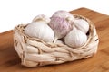 Garlic cloves in wicker basket on board