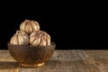 Garlic in dark bowl on wooden table. Isolated on black