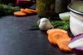 Garlic, dill, cut carrot, cut red onion, boiled egg near iron tureen and bowl of sorrel on dark wooden table. Royalty Free Stock Photo