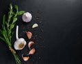 Garlic, garlic cloves surrounded by herbs and spices, on a black stone table