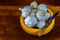 Garlic in hand turned hardwood bowl on a reclaimed hard wood background.