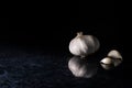 A garlic head with garlic cloves on a black and silver kitchen top background.