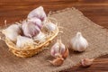 Garlic horizontal banner. Eco farming concept. Whole garlics and cloves in straw basket on piece of sacking on brown wooden textur