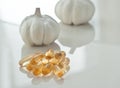 Garlic oil capsules on a white reflective surface