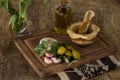 Garlic, parsley and green olives on table with stone mortar