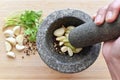Garlic, peppercorns and coriander roots in a gray granite mortar.