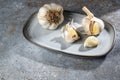 Garlic on a plate and a grey stone background, the healthy cloves lower blood pressure and inhibit bacteria and fungi, copy space