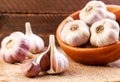 Garlic in a plate whole and a clove of garlic on a wooden background