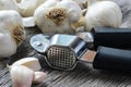 Garlic Press and Garlic Bulb Close Up on Rustic Wood