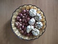 Garlic and red onions in a wicker plate with a background wooden table