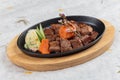 Garlic Saikoro Steak: medium rare dice wagyu topping with mince carrot on hot plate served with potato salad. Royalty Free Stock Photo