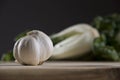 Garlic on wood cutting board with bok choy in the background