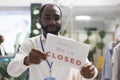 Garment department store african american employee hanging closed sign Royalty Free Stock Photo