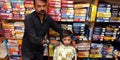 Garment shopkeeper showing tshirt to the child customer at showroom