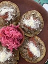 Garnachas appetizer served on clay plate. Crispy corn tortilla served with shredded beef, salsa, cheese, and pickled cabbage.