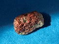 Garnet almandine stone crystal inside rock. A mineral isolated on blue background. Found near Miass city, Ural, Russia