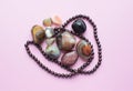 Garnet beads and round agate bostwan stones on pink background. Multicolored gemstones, tumbled minerals